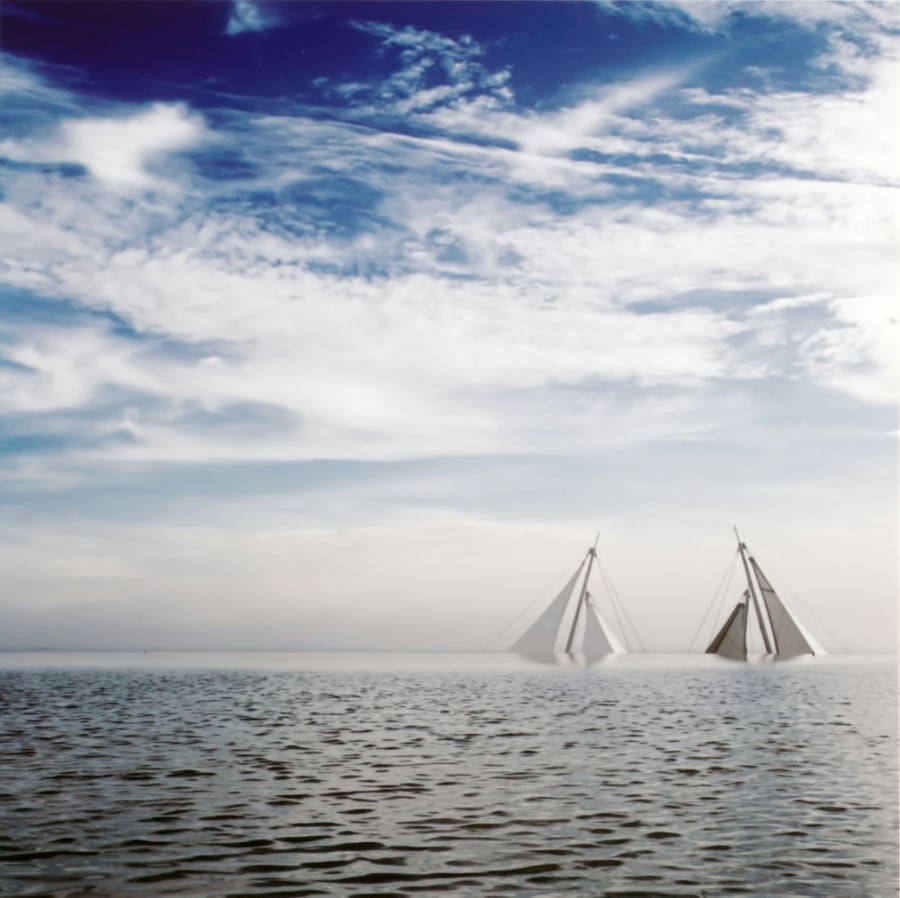 photography of a sea, there are two boats. shoes a blue cloudy sky